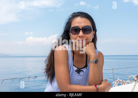 Frau mit Sonnenbrille auf Segelboot auf der Suche nach Fotograf Stockfoto