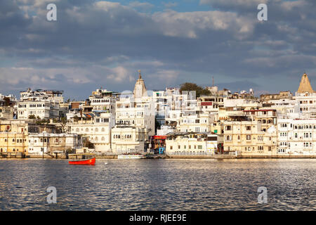 Pichola-See mit Stadtschloss Blick auf Sonnenuntergang Wolkenhimmel in Udaipur, Rajasthan, Indien Stockfoto