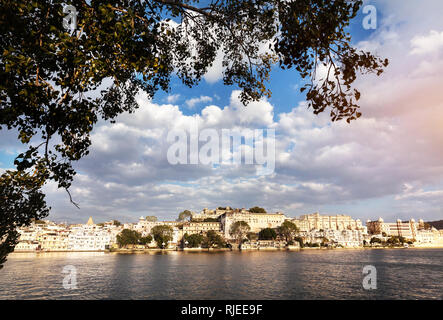 Pichola-See mit Stadtschloss Blick auf Sonnenuntergang Wolkenhimmel in Udaipur, Rajasthan, Indien Stockfoto