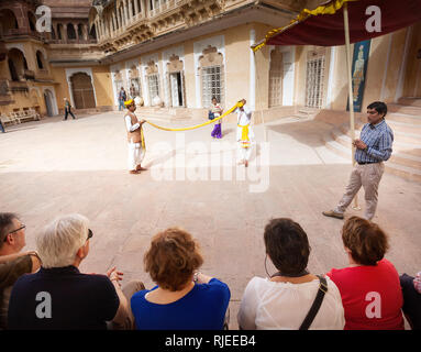 JODHPUR, Rajasthan, Indien - MÄRZ 08, 2015: Zwei Männer in traditionellen Rajasthan Tuch zeigen, wie Turban von der gelben Tuch vor der Gruppe von t machen Stockfoto