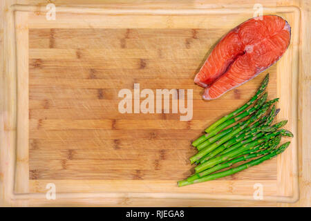 Frischer Lachs Steak mit Spargel auf einer hölzernen Schneidebrett Stockfoto