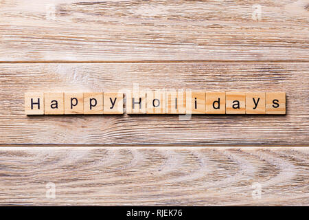 Happy Holidays Wort auf Holz Block geschrieben. Frohe Weihnachten text auf Holz- Tabelle für Ihr Design, Konzept. Stockfoto