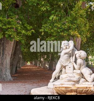 Eine Statue von zwei Zahlen in öffentlichen Gärten vor einer grünen Allee. Blätter im Herbst Teppich boden. Stockfoto