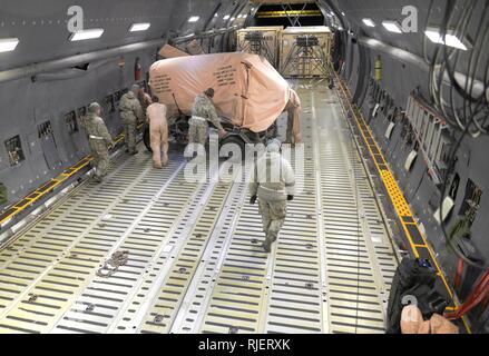 Us-Flieger vom 106 Rettung Flügel an der New York Air National Guard zugeordnet und loadmasters aus dem 9. Airlift Squadron aus Dover Air Force Base, Del., Manöver cargo innerhalb einer C-5 M Super Galaxy Flugzeug in Francis S. Gabreski Air National Guard Base, N.Y., Jan. 23, 2018. Loadmasters direkt die Ladung Team Wo und Ladungssicherung, das Flugzeug zu sorgen für einen sicheren Flug ausgeglichen ist. Stockfoto