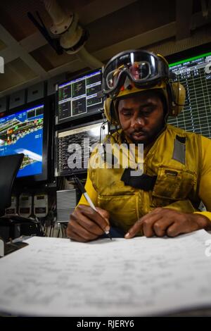 ARABIAN GULF (Jan. 15, 2018) der Luftfahrt Bootsmann Mate (Handling) 1. Klasse Paul Halle schafft eine Uhr Bill für die Handhabung von Flugzeugen in Flight Deck Control an Bord der Flugzeugträger USS Theodore Roosevelt (CVN 71). Theodore Roosevelt und ihre Carrier strike Group werden in den USA 5 Flotte Bereich für Maßnahmen zur Erhöhung der Sicherheit im Seeverkehr im Einsatz Verbündeten und Partnern zu beruhigen und der Freiheit der Schiffahrt und des freien Handels in der Region erhalten. Stockfoto