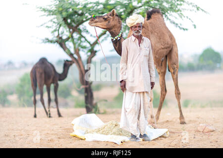 Indische Männer und sein Kamel in der Wüste Thar in Pushkar Kamel Mela in der Nähe der heiligen Stadt Pushkar. Diese Messe ist die größte Camel Trading Messe der Welt. Stockfoto