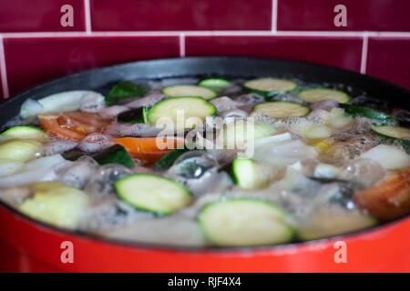 Roten Topf mit siedendem Gemüsesuppe. Close-up mit Schaum und Blasen. Stockfoto