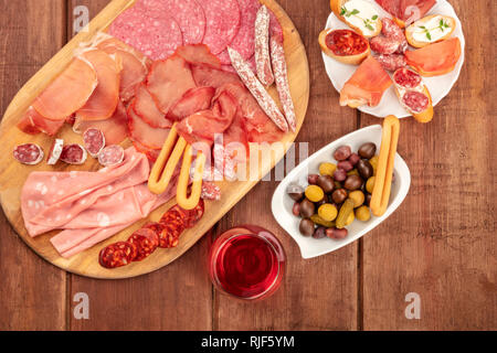 Charcuterie Verkostung. Ein Foto von vielen verschiedenen Wurst und Schinken, Aufschnitt, Schuß von der Oberseite in einem dunklen rustikalen Hintergrund Stockfoto