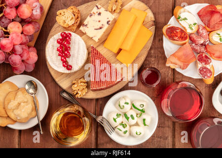 Eine Auswahl an Käse, Schinken und Weine, die Weinprobe und das Pairing, Schuß von der Oberseite in einem dunklen Holzmöbeln im Landhausstil Hintergrund Stockfoto