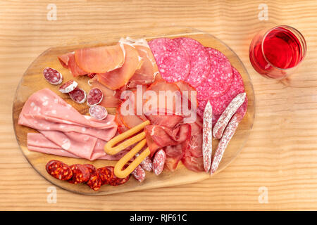 Charcuterie Verkostung. Ein Foto von einem Fach mit vielen verschiedenen Wurst und Schinken, Aufschnitt, geschossen von oben auf eine rustikale Hintergrund mit Wein Stockfoto