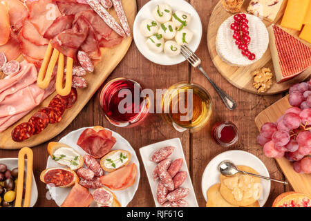 Charcuterie Verkostung. Viele verschiedene Wurst und Schinken, Aufschnitt, und einer Auswahl an Käse, geschossen von oben auf eine rustikale Hintergrund mit Brille Stockfoto