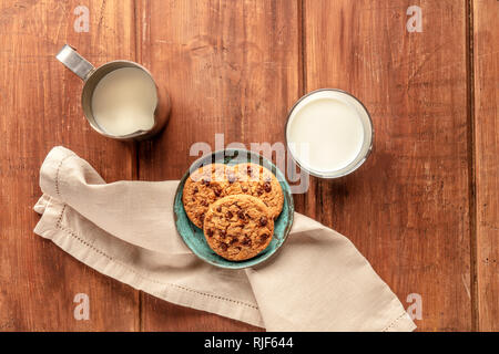 Ein Foto von Chocolate Chip Cookies auf einer dunklen Holzmöbeln im Landhausstil Hintergrund mit Milch und einen Platz für Text Stockfoto