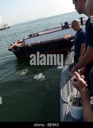 MINA SALMAN PIER, Bahrain (Jan. 24, 2013) Marine Taucher zu mobilen Tauchen und Bergung (MDSU) 2, 2-2, die tendenziell Line Control und für Taucher warten, während eine Routine zur Oberfläche - Terrorismus Force Protection dive zugeordnet. MDSU 2 ist es, Commander, Task Group 56.1 zugewiesen, die Förderung der Mine Countermeasure, Beseitigung von Explosivstoffen, bergung Tauchen und Schutz in den USA 5 Flotte Verantwortungsbereich. Stockfoto