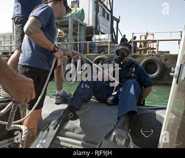 Marine Diver 3. Klasse Joe Ziemba, rechts, von Navy Diver 2. Klasse Matthew Cortez, sowohl für Mobile Tauchen und Bergung (MDSU) 1, 1-5, das Wasser tritt für eine Anti-terror-Force Protection dive Operation zugewiesenen gepflegt. MDSU 1 ist mit Commander Task Group (CTG) 56,1, die eine Mine Countermeasure, Beseitigung von Explosivstoffen (EOD), Bergung - Tauchen, Terrorismusbekämpfung, und Schutz für die USA 5 im Einsatz. Stockfoto