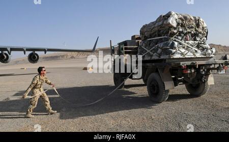 Die Royal Australian Air Force airman wirft ein Zurrgurt über der Oberseite der Palette an mehreren nationalen Tarin Kot, Afghanistan, 05 Dez. 2010. In einem Monat, der TK Luftbewegung Team geschickt, die mehr als 686,000 Pfund von Fracht. Stockfoto