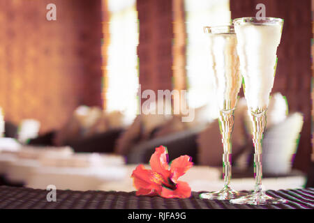 Zwei Gläser Champagner mit roter Blume in einem Spa Lounge. Spa Konzept. Spa Lounge. Valentines Hintergrund. Romantik Konzept. Horizontale. Glitc Stockfoto