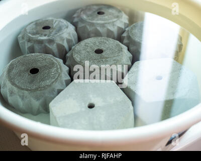 Verschiedene geometrische konkrete Pflanzer aus weißem Kunststoff Waschbecken mit Wasser den PH-Wert des konkreten Töpfe zu verringern. Stockfoto