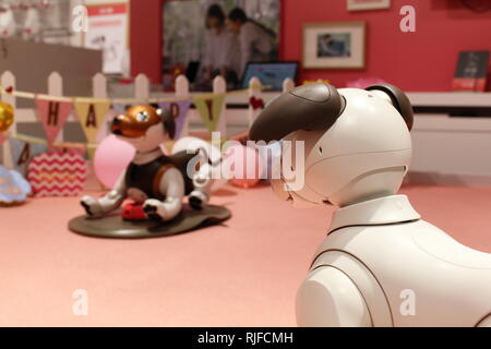 Ein paar der AIBO Roboter Hunde, eine nach der anderen auf einem Ladegerät suchen, auf der ein Valentinstag-themed play Bereich in einem Sony Showroom. Stockfoto