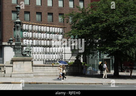 Überqueren von Nihonbashi Brücke. Gibt es ein Festival in der Nähe, so mit Laternen geschmückt ist. Nomura Securities Hauptsitz befindet sich im Hintergrund. Stockfoto