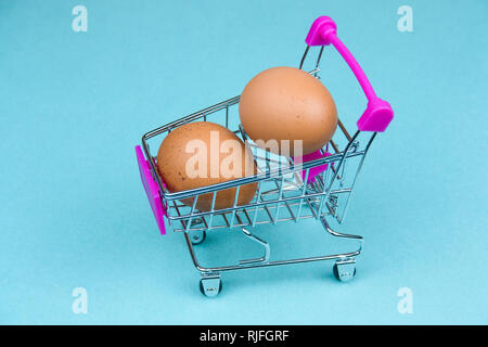 Braune Eier in Shopping Card auf einem blauen Hintergrund Stockfoto