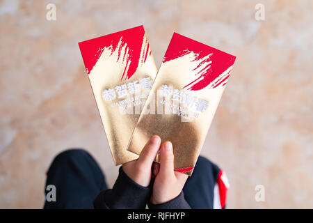 Kid holding Paar rote Taschen Übersetzung - Frohes Chinesisches neues Jahr Stockfoto