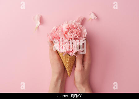 7/8 Schuß von Frau mit wafer Kegel mit schöne zarte Blumen isoliert auf Rosa Stockfoto