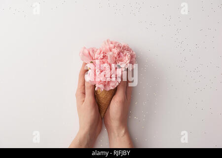 Teilweise mit Blick auf die Frau mit Waffel Kegel mit schönen rosa Blumen isoliert auf Grau Stockfoto