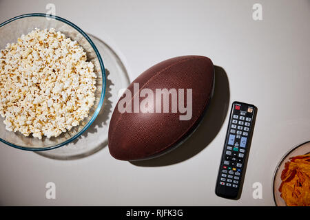 Blick von oben auf die köstliche Snacks in Glasschalen in der Nähe von Fußball und Fernbedienung auf weißem Hintergrund Stockfoto