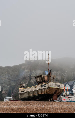 Hastings, East Sussex, Großbritannien. Februar 2019. Wetter in Großbritannien: Dichter Nebel steigt über die Fischerboote herab, die den East Hill Lift fast verdecken. Ein dumpfer feuchter Tag, aber bei fast 9 Grad viel wärmer Stockfoto