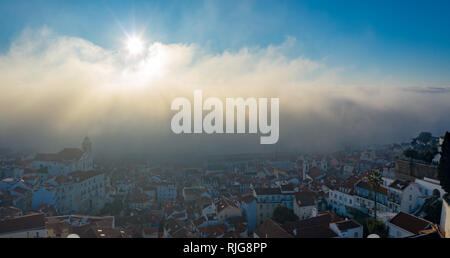 Antenne; nebligen Morgen im antiken Viertel Alfama der portugiesischen Hauptstadt; drone Blick auf hübsche kleine Häuser, Sonne über den Wolken steigend; Nat Stockfoto