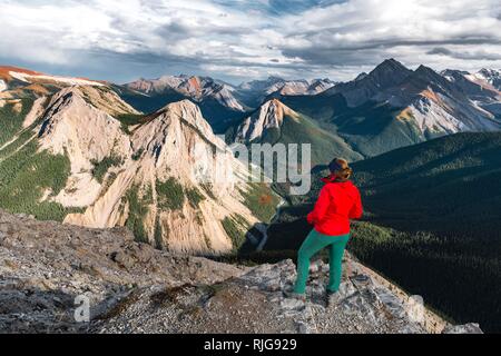 Weibliche Wanderer sieht von Gipfel über Berge, Gipfel mit orange Schwefelablagerungen, Panoramaaussicht Stockfoto