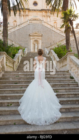 Anmutige Braut klettert die steinernen Treppen in einem Hochzeitskleid Stockfoto