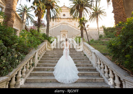 Anmutige Braut klettert die steinernen Treppen in einem Hochzeitskleid Stockfoto