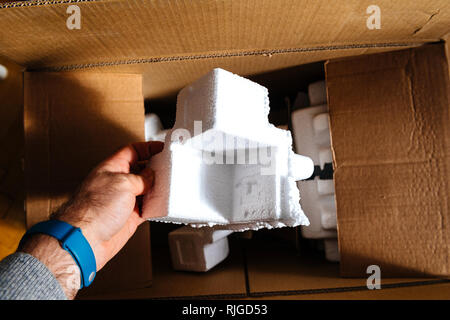 Mann mit Styropor Verpackung Detail aus einem Karton während Unboxing Stockfoto