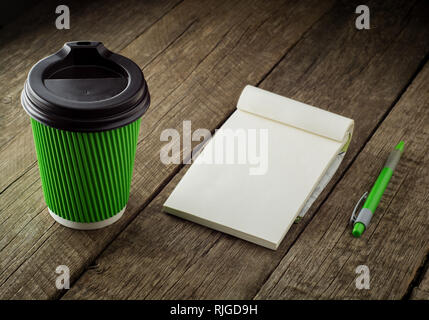 Pen, Notebooks und Kaffee Tasse auf rustikalen Holztisch im Außenbereich am Morgen. Stockfoto