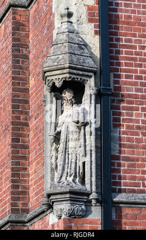 Mittelalter historische steinerne Statue in einem aedicule an der Ecke einer roten Backsteingebäude, sehr verwittert und abgenutzt, in Arundel, West Sussex, UK. Stockfoto