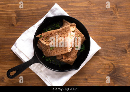Essen Konzept hausgemachten Schinken und Käse Krepp in Iron Skillet auf Holz Hintergrund cast Stockfoto