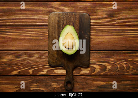 Blick von oben auf die Schneiden avocado auf hölzernen Hintergrund Stockfoto