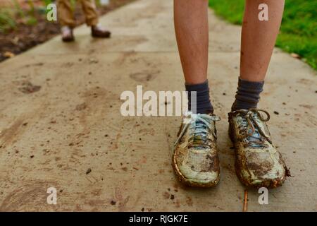 Schlammigen Schuhen auf junge Kinder im schulpflichtigen Alter nach einem Spaziergang entlang einem Feldweg, Moongun Wanderweg am Elliot Federn, Townsville, Queensland, Australien Stockfoto