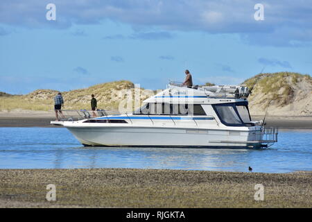 Motor starten mit drei Mann Besatzung langsam voran durch die engen Hafen Kanal mit Flachbild Shell Beach auf der einen und Dünen auf der anderen. Stockfoto