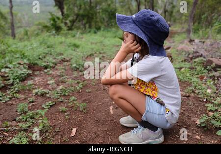 Junge schulpflichtige Mädchen Langweilten oder in der Verzweiflung allein auf einem Feldweg, Moongun Wanderweg am Elliot Federn, Townsville, Queensland, Australien Stockfoto