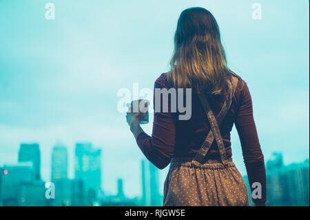 Eine junge Frau trinkt Kaffee in einer City Apartment Stockfoto