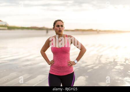 Läuferin erholt, nachdem sie auf einem Strand bei Sonnenaufgang Stockfoto