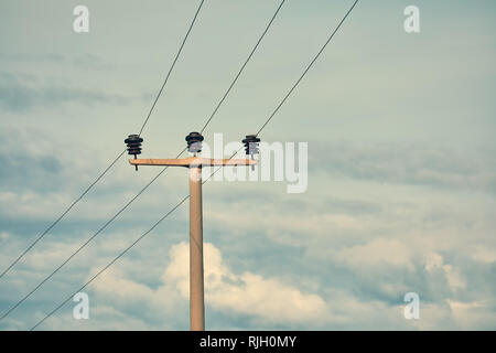 Minimalistische Ansicht einer konkreten Hochspannungsleitungen elektrische Pole, Stromleitungen und Sicherungen gegen eine trübe und blauer Himmel. Stockfoto