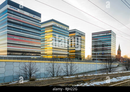 Kattowitz, Schlesien, Polen: 19. Januar 2019: Tiramisu business center Gebäude in Kattowitz, Polen mit einer nahe gelegenen Straßenbahn Linie und eine neogotische Kirche Stockfoto