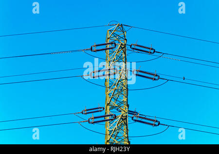 Power line Überfahrt mit einem kleinen Vogel sitzt auf einem Draht gegen den klaren blauen Himmel an einem sonnigen Tag Stockfoto