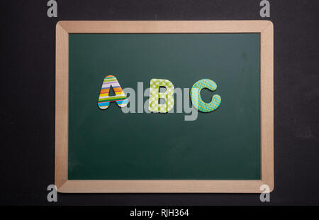 Abc, Alphabet, Schule Konzept. ABC Text mit bunten Buchstaben auf dem grünen Brett mit Holzrahmen, schwarz Farbe Hintergrund Stockfoto