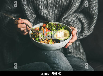 Frau in Pullover das Essen von frischem Salat, Avocado, Bohnen und Gemüse Stockfoto