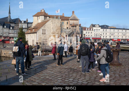 Eine japanische Reisegruppe genießen Sie den Hafen oder Vieux Bassin in Honfleur, Normandie, Frankreich mit der antiken Gebäude La Lieutenance hinter sich. Stockfoto