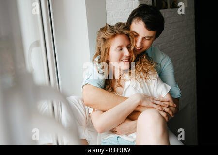 Glückliches Mädchen und Mann umarmen in der Nähe der Fenster in der Startseite. Stockfoto